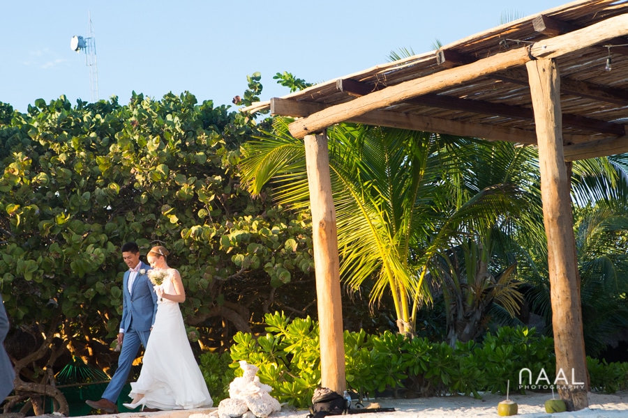 Bride and groom walking to the aisle at Blue Venado beach Club by Naal Wedding Photography
